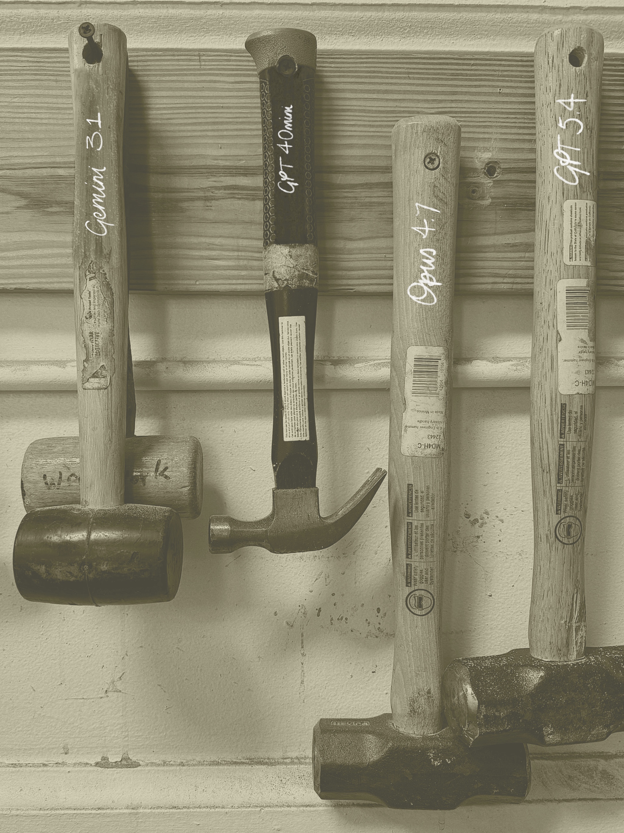 A row of hammers of varying sizes and shapes hanging on a workshop wall, from small tack hammers up to heavy mallets.