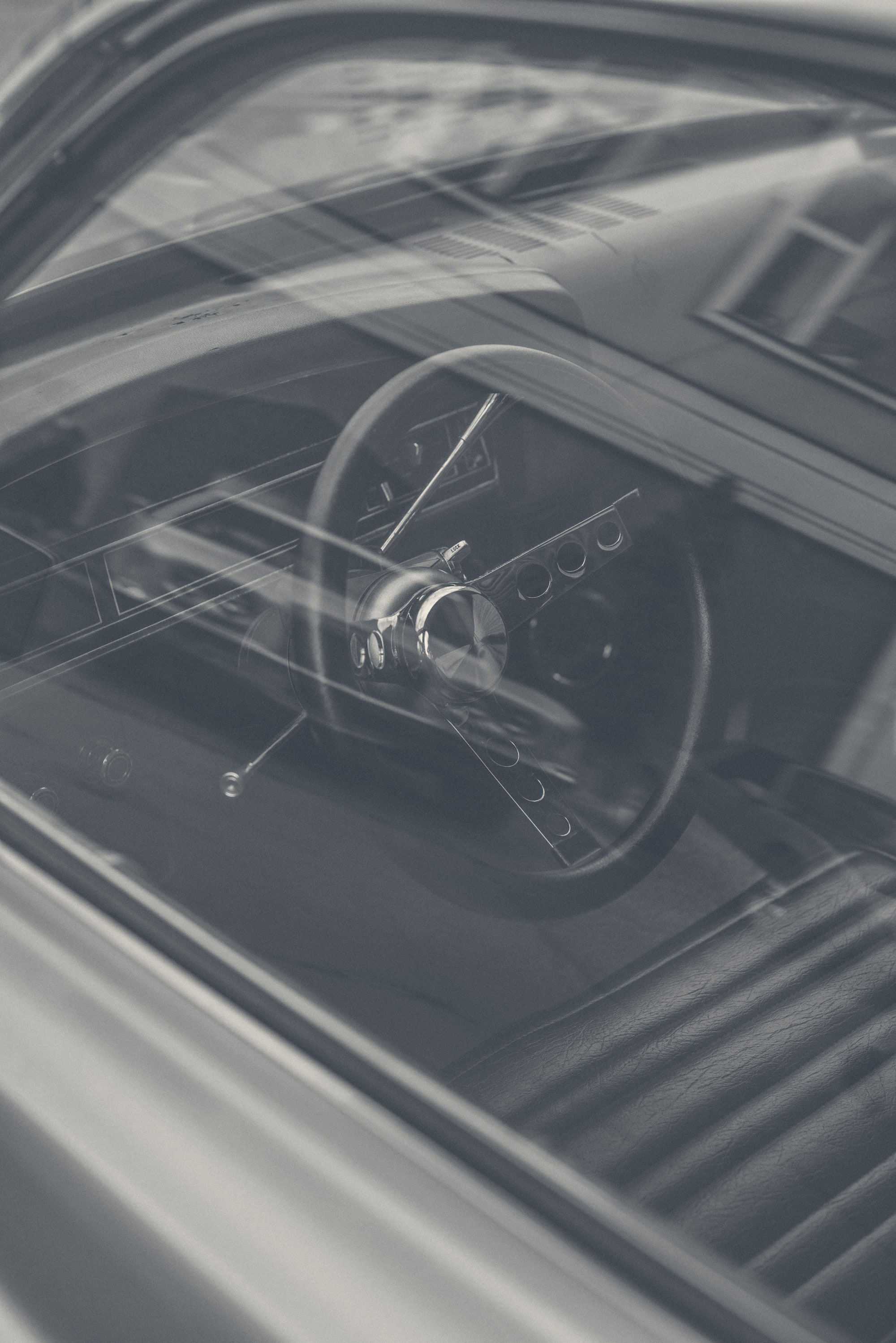 A black-and-white close-up of a car door and the edge of its window, photographed at low angle in stark contrast.